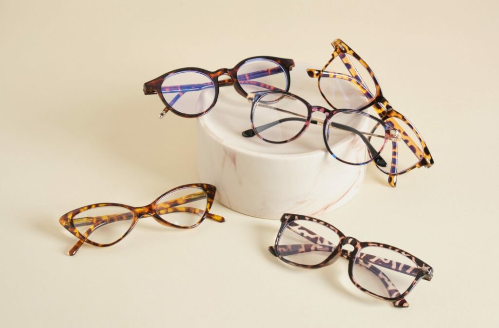 Several stylish pairs of eyeglasses are arranged on a beige background.