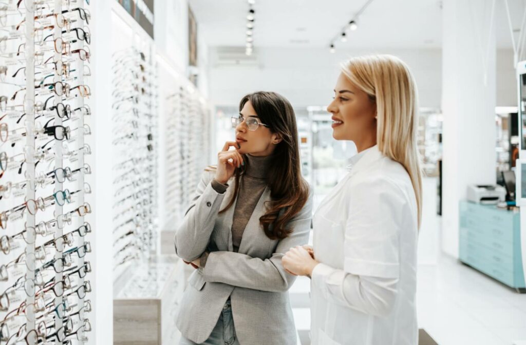 An advisor smiles and points out some eyeglasses options for a client with an oval-shaped face.
