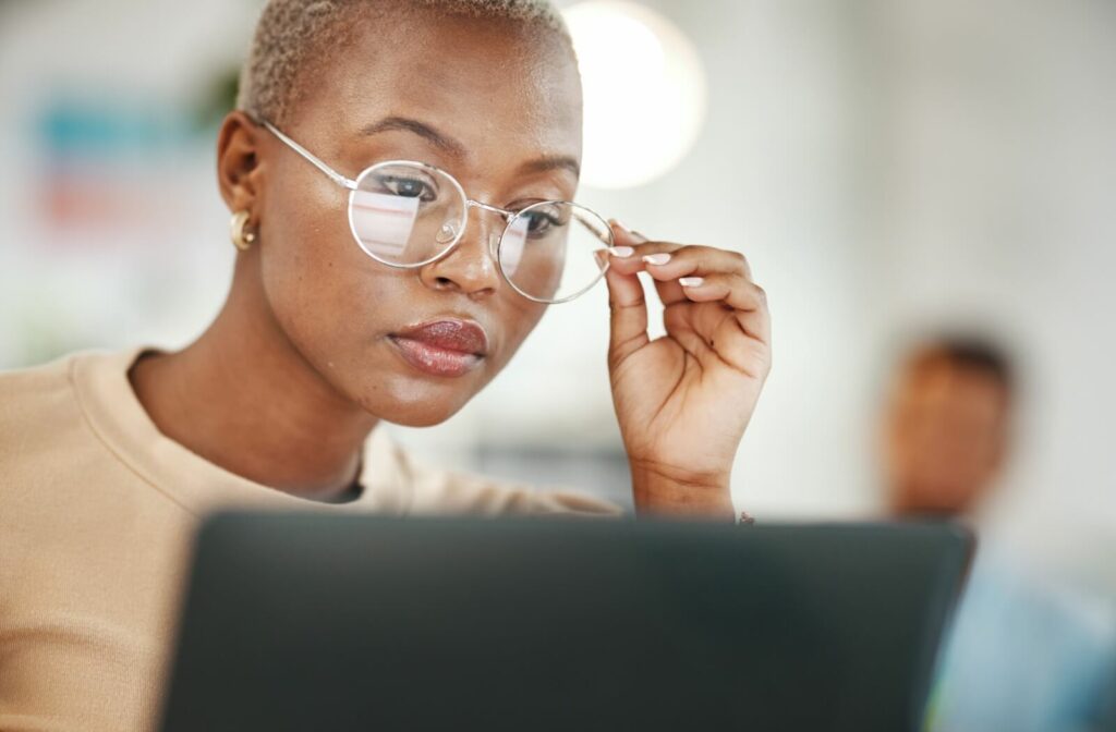 Person wearing glasses working on a laptop computer.